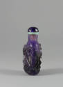 Carved Purple Snuff Bottle, early 20th century
China
Fluorite and jade; 3 1/8 × 1 7/8 × 1 1/4…